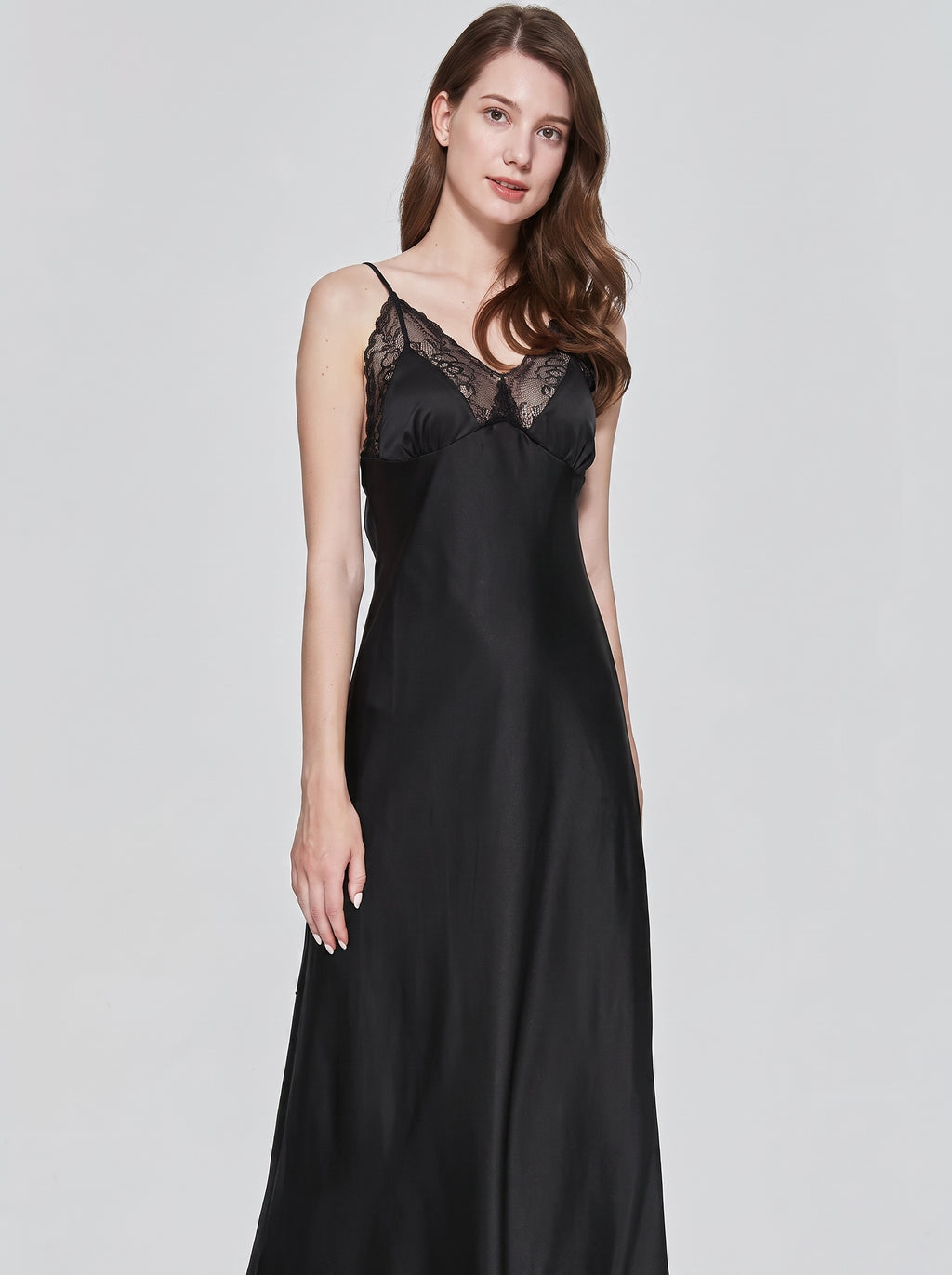 Modele souriant portant la nuisette longue noire en satin de trois-quarts, reflets soyeux