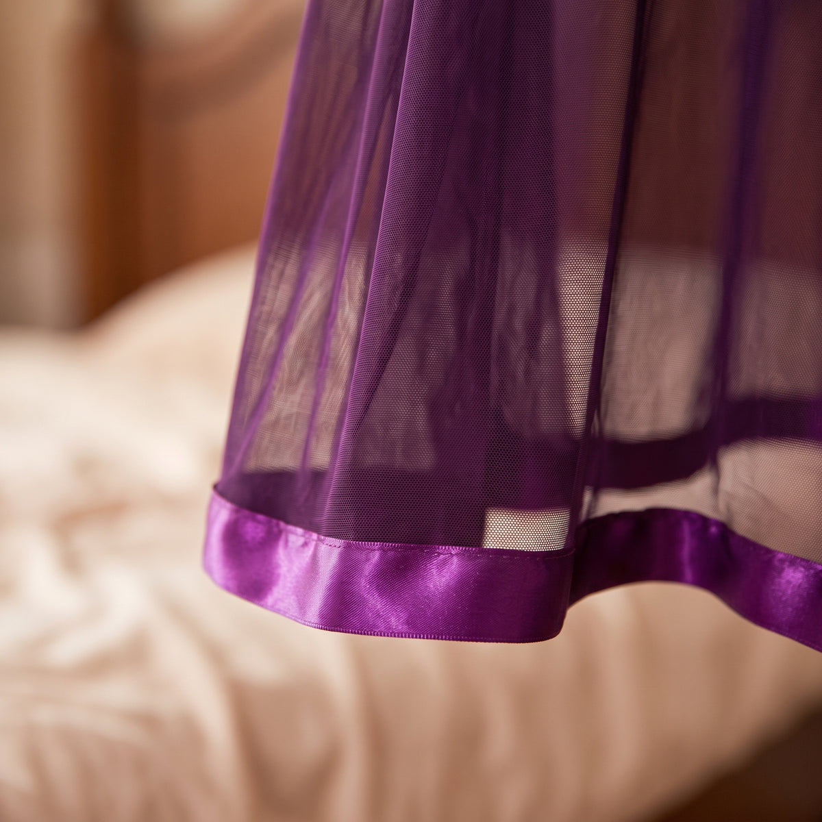 Gros plan sur l'ourlet en satin violet brillant et le voile transparent de la nuisette
