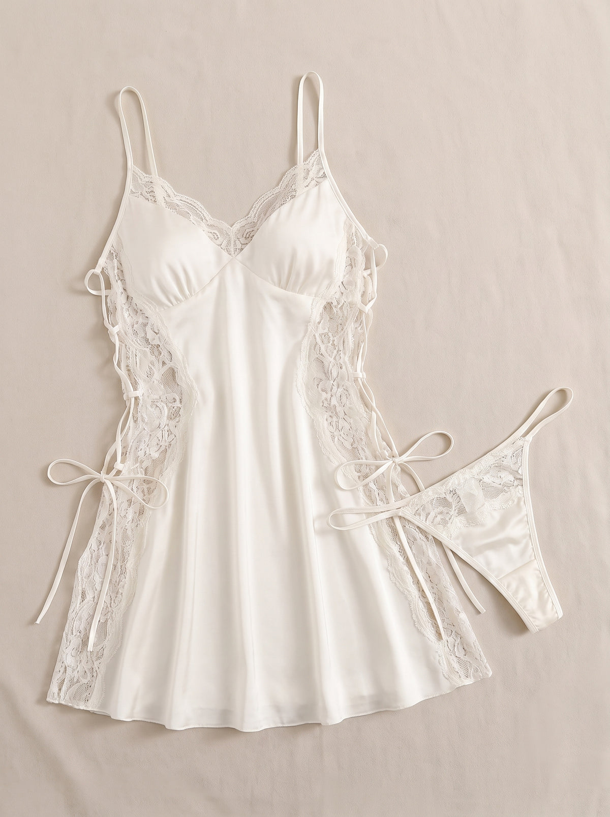 Nuisette en satin ivoire à côtés lacés et dentelle, avec string assorti, présentée à plat