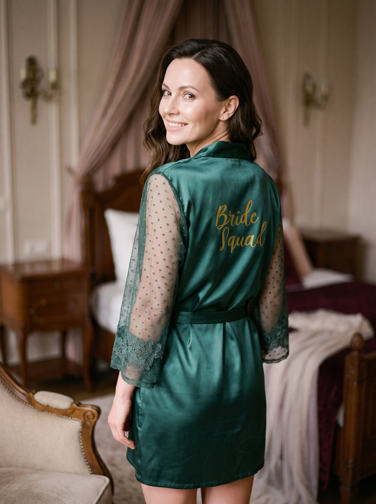 Femme souriante portant le peignoir vert Bride Squad dans un boudoir