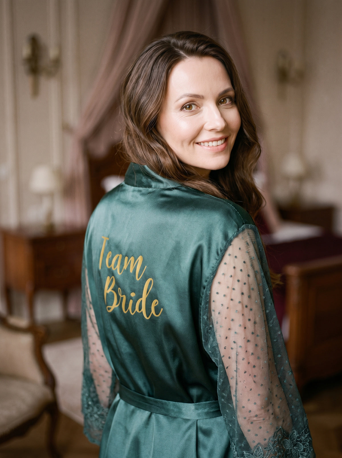 Femme souriante portant le peignoir vert Team Bride dans un boudoir