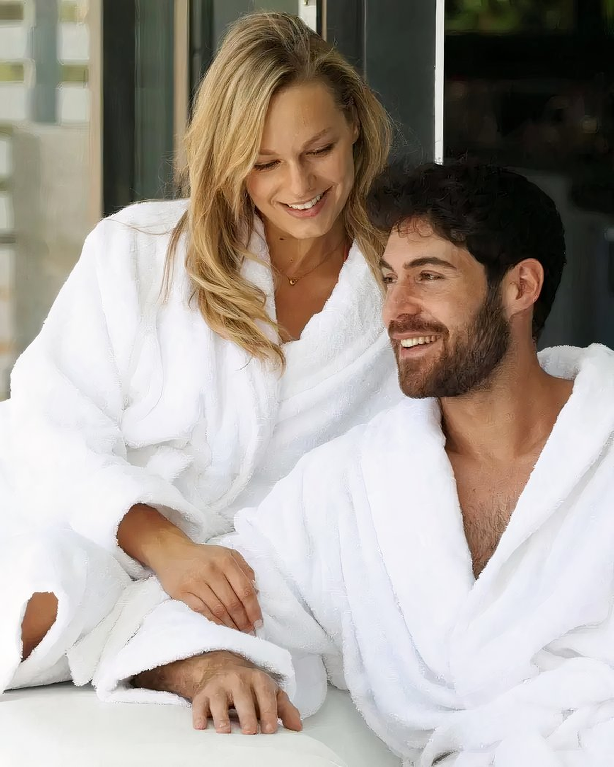 Couple souriant en peignoir de bain blanc dans un intérieur lumineux