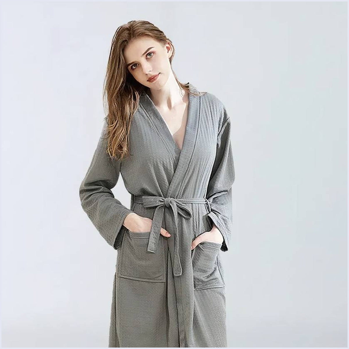 Femme portant un peignoir de bain gris devant le miroir le matin Image