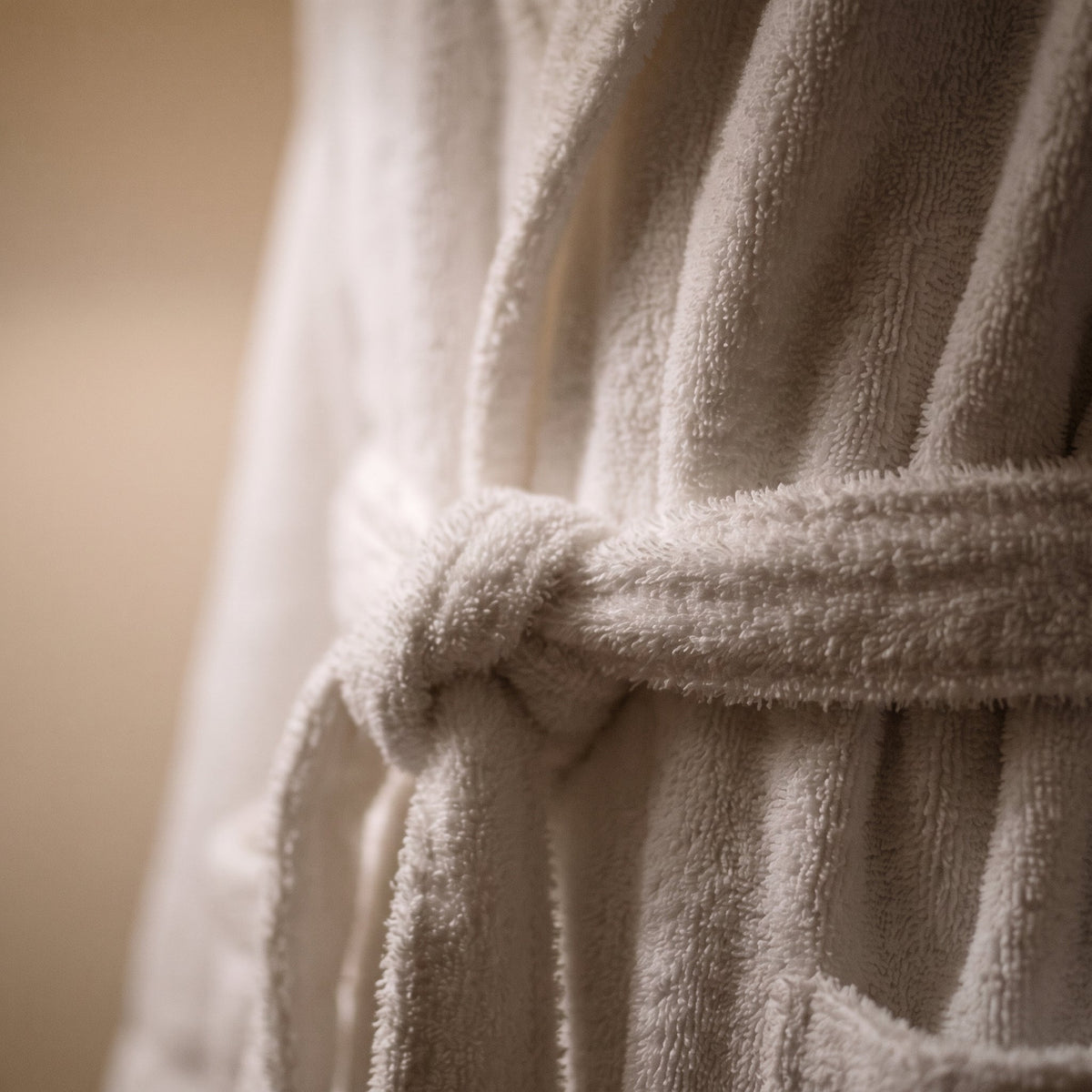 Gros plan sur le tissu eponge epais et la ceinture nouee du peignoir, illustrant le confort enveloppant