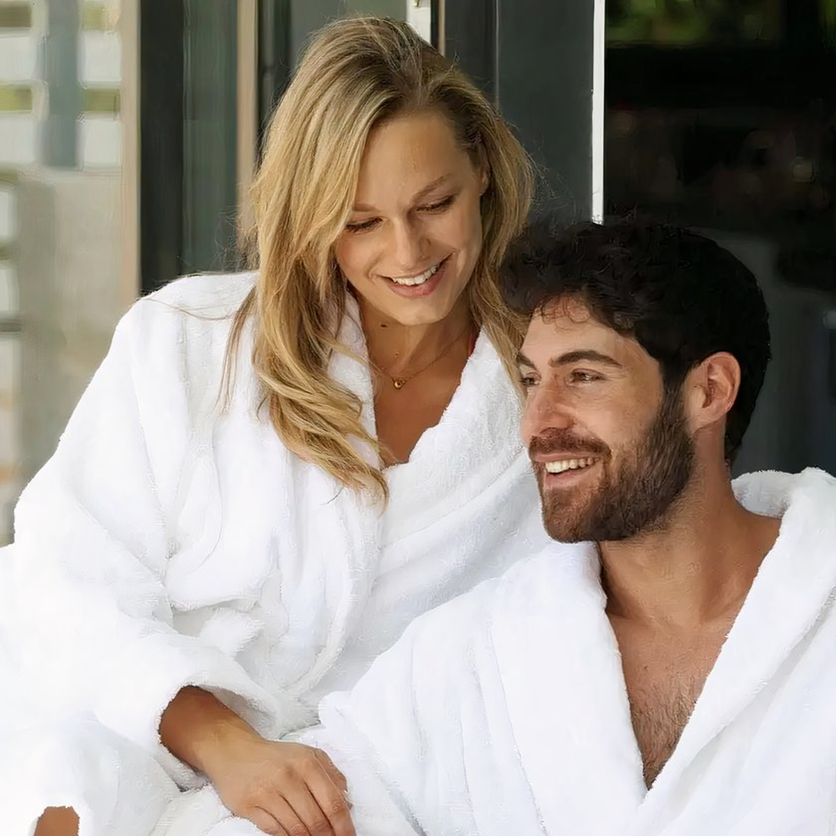 Couple souriant en peignoir de bain blanc pendant un moment calme Image