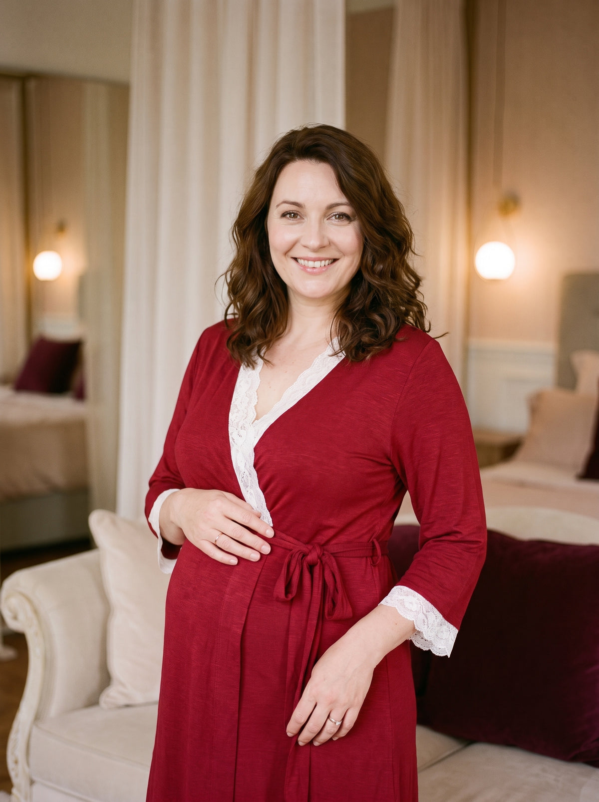 Future maman souriante portant le peignoir de maternité rouge dans un boudoir