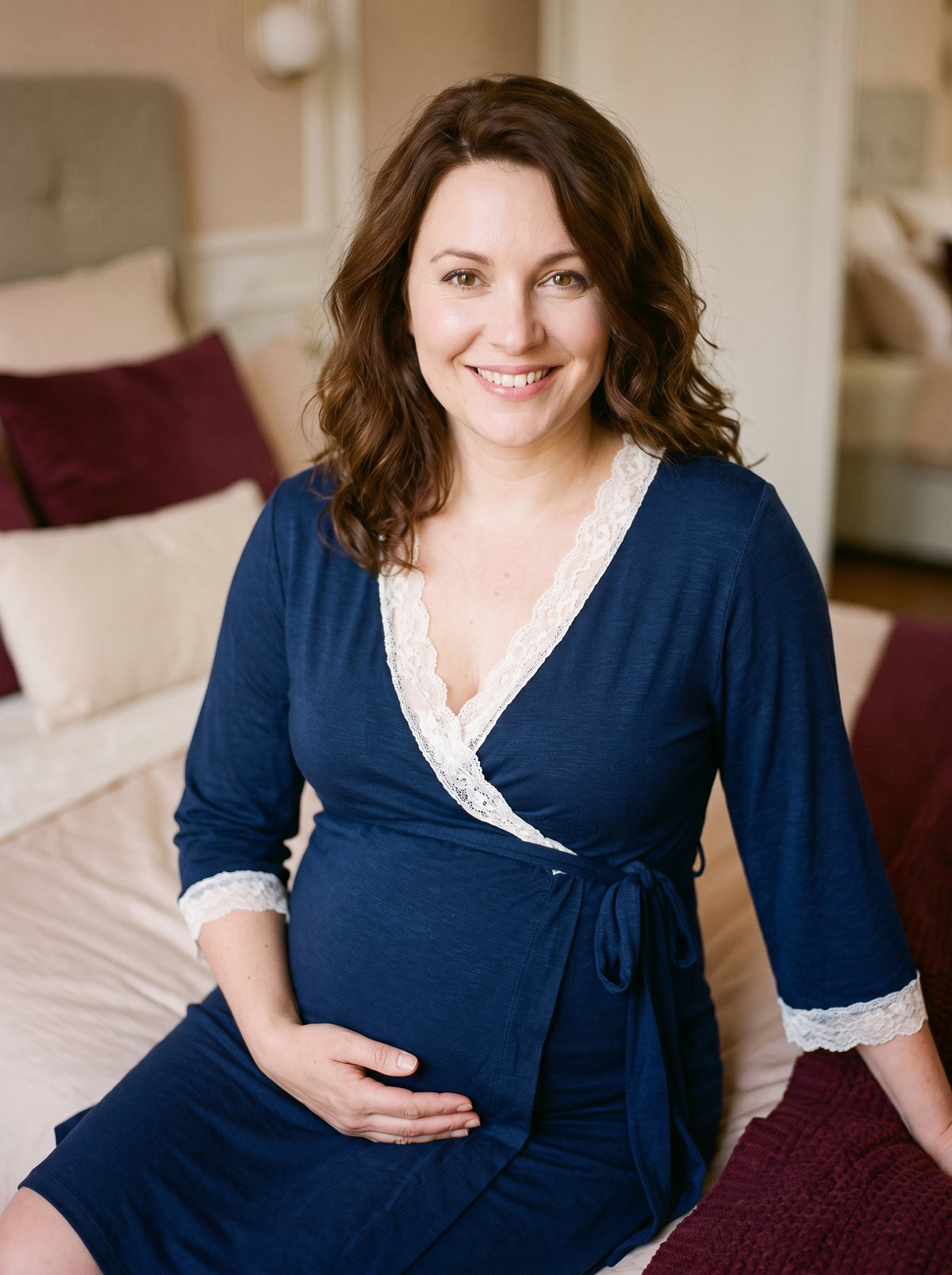 Future maman souriante portant le peignoir de maternité bleu dans un boudoir