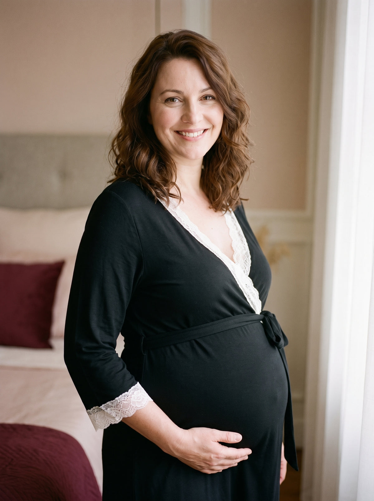 Future maman souriante portant le peignoir de maternité noir dans un boudoir
