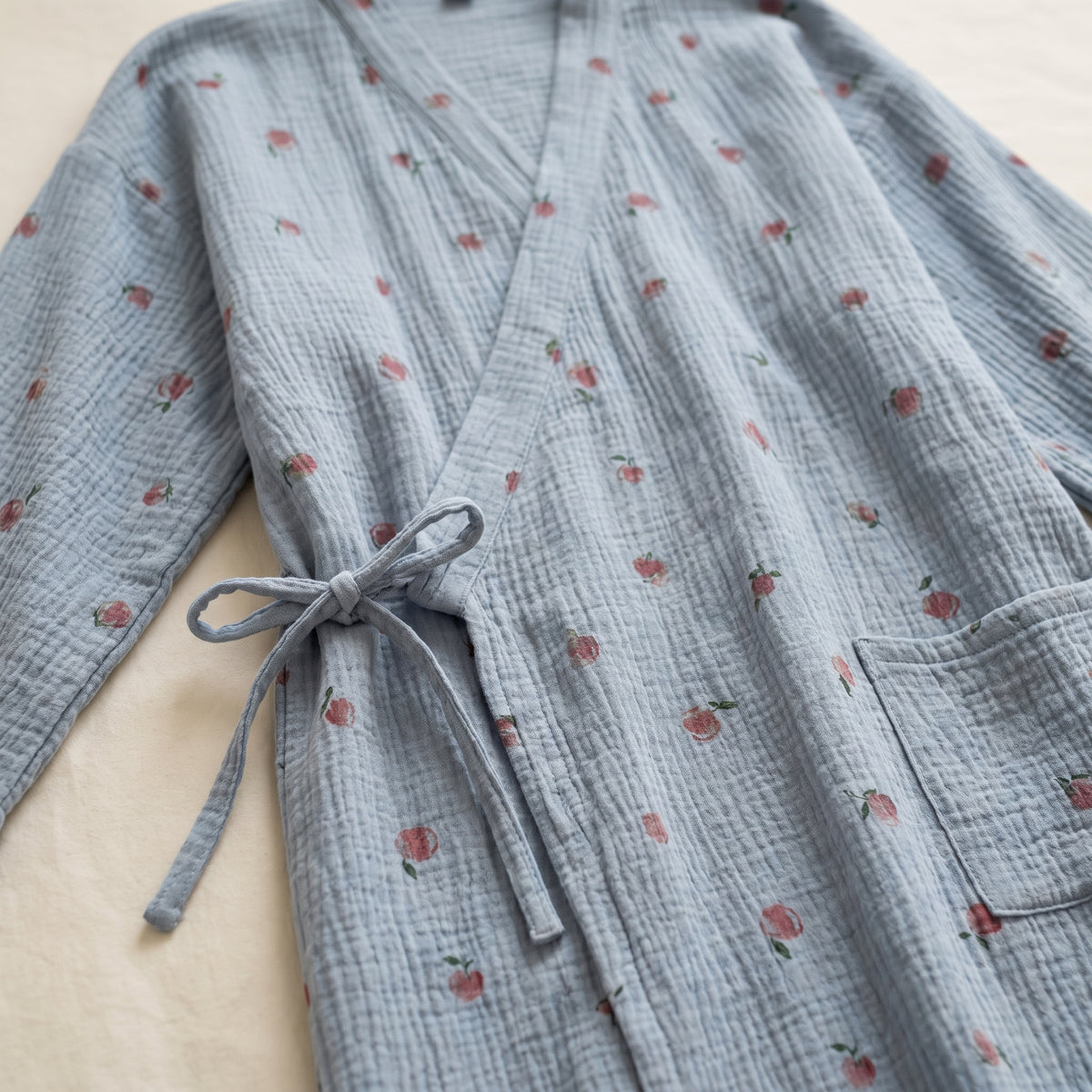 Gros plan sur le col, le lien latéral et la poche du peignoir kimono floral bleu