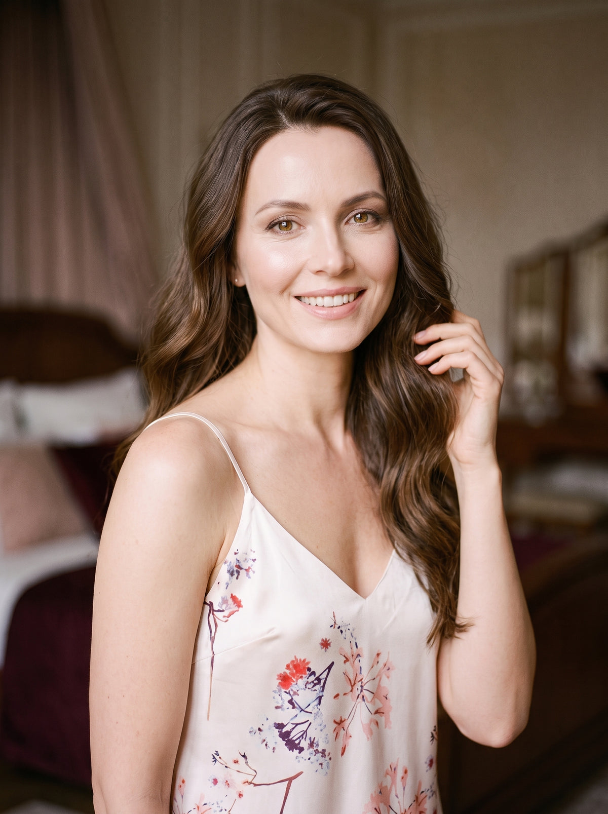 Femme souriante portant la nuisette courte en satin rose à motifs floraux devant une coiffeuse de chambre