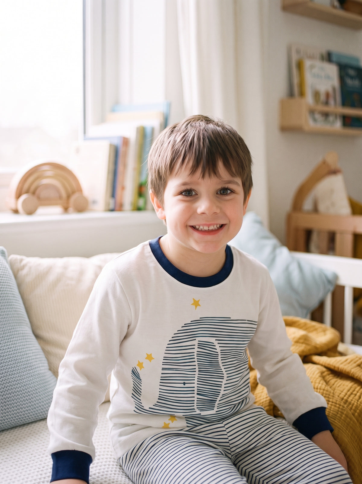 Petit garçon souriant portant le pyjama blanc à l'éléphant et aux étoiles