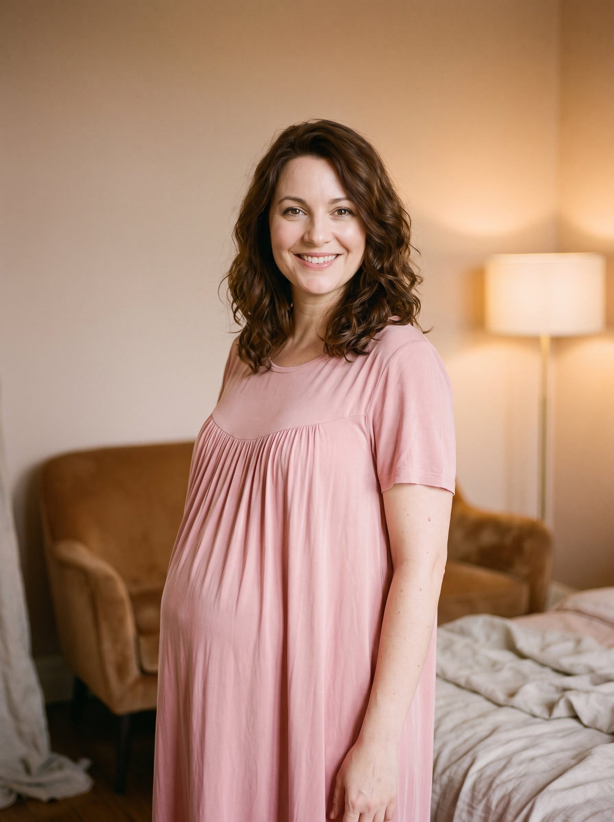 Femme enceinte souriante portant la chemise de nuit rose poudré en coton