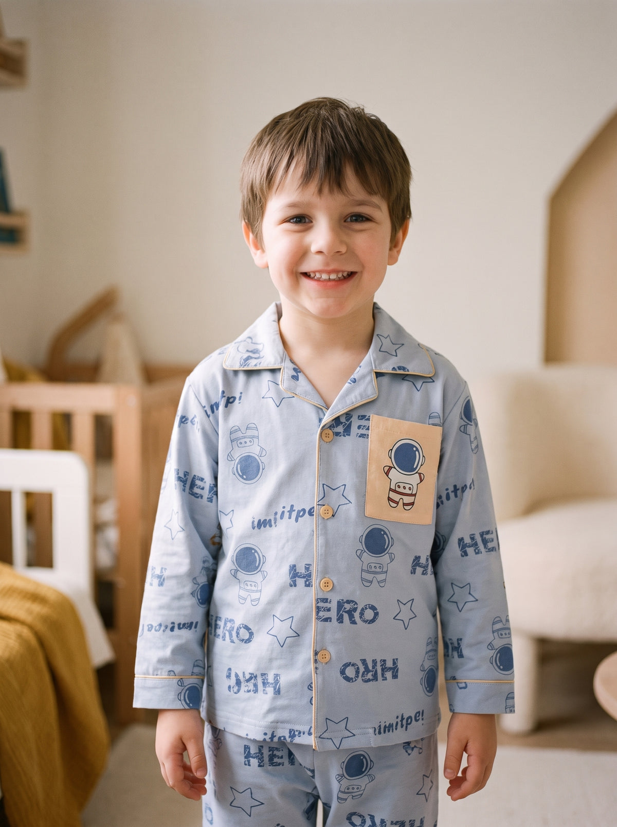 Garçon souriant portant le pyjama astronaute bleu ciel dans une chambre chaleureuse