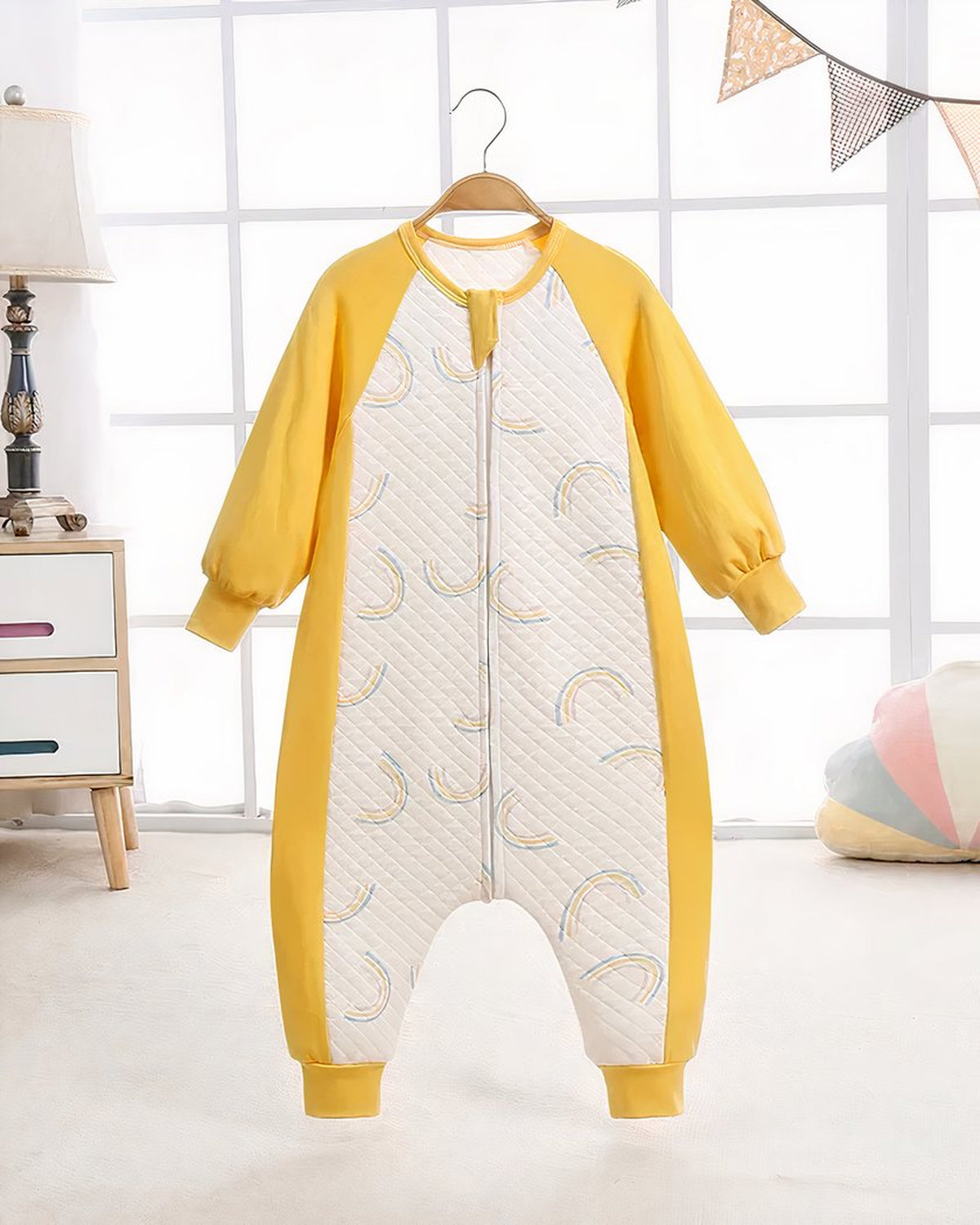 Pyjama enfant à arcs-en-ciel suspendu sur cintre, présenté en entier dans une chambre