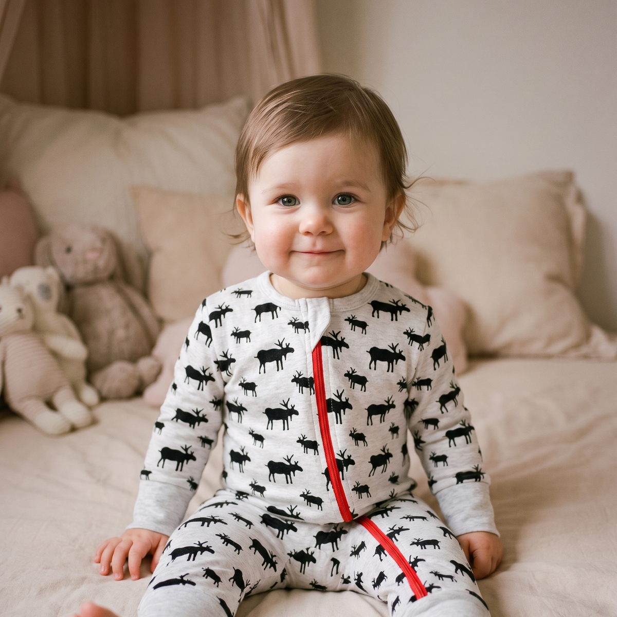 Bébé souriant assis dans le pyjama gris clair à silhouettes de rennes