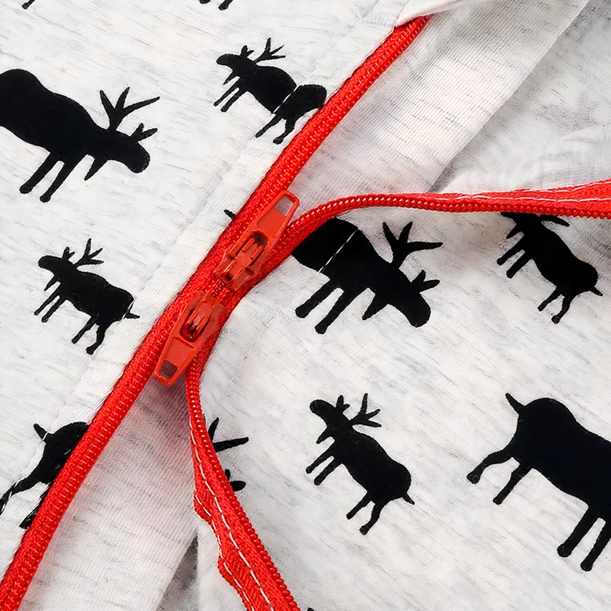 Gros plan sur la fermeture rouge et les motifs de rennes noirs du pyjama bébé