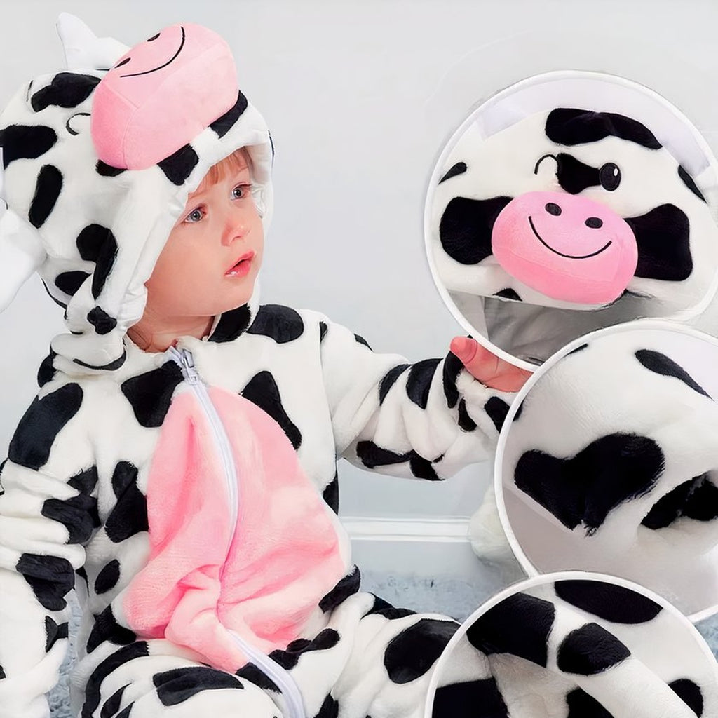 Matière pelucheuse du pyjama vache portée par un bébé assis, capuche et ventre rose vus de près