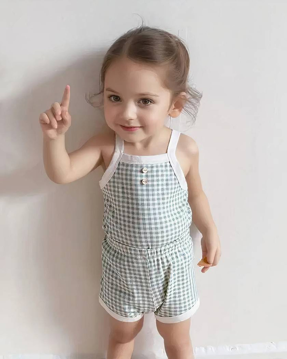 Bébé souriant debout portant le pyjama d’été vert à carreaux, débardeur et short