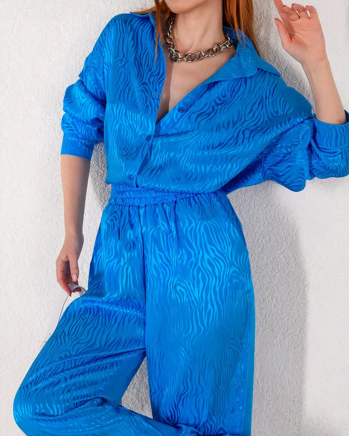 Ensemble de pyjama bleu satiné porté debout, chemise ouverte sur le devant et pantalon à jambes larges