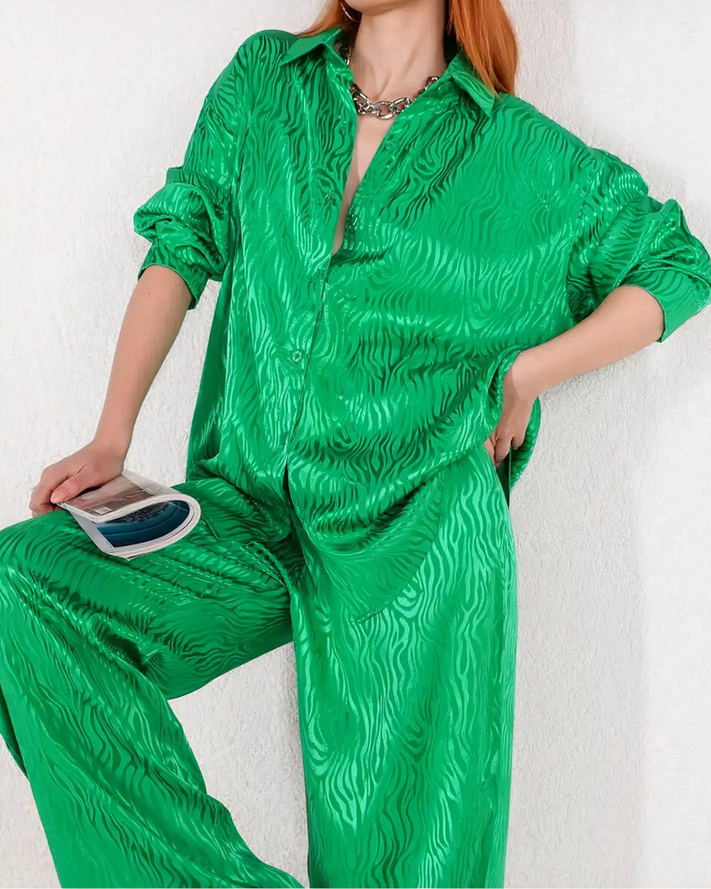 Ensemble de pyjama vert satiné porté debout, chemise ouverte sur le devant et pantalon à jambes larges