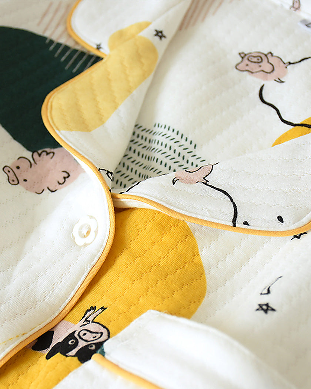 Détail du col boutonné et du passepoil jaune du pyjama à imprimés animaux