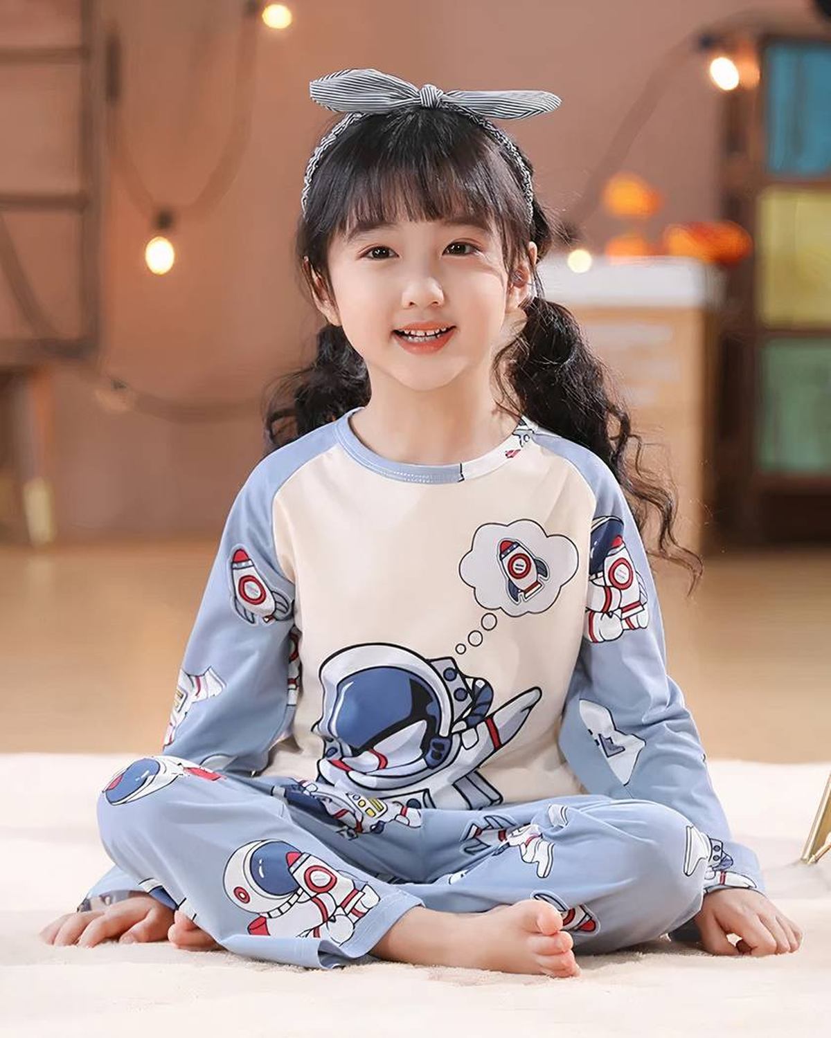 Fille souriante portant le pyjama astronaute bleu de mi-saison