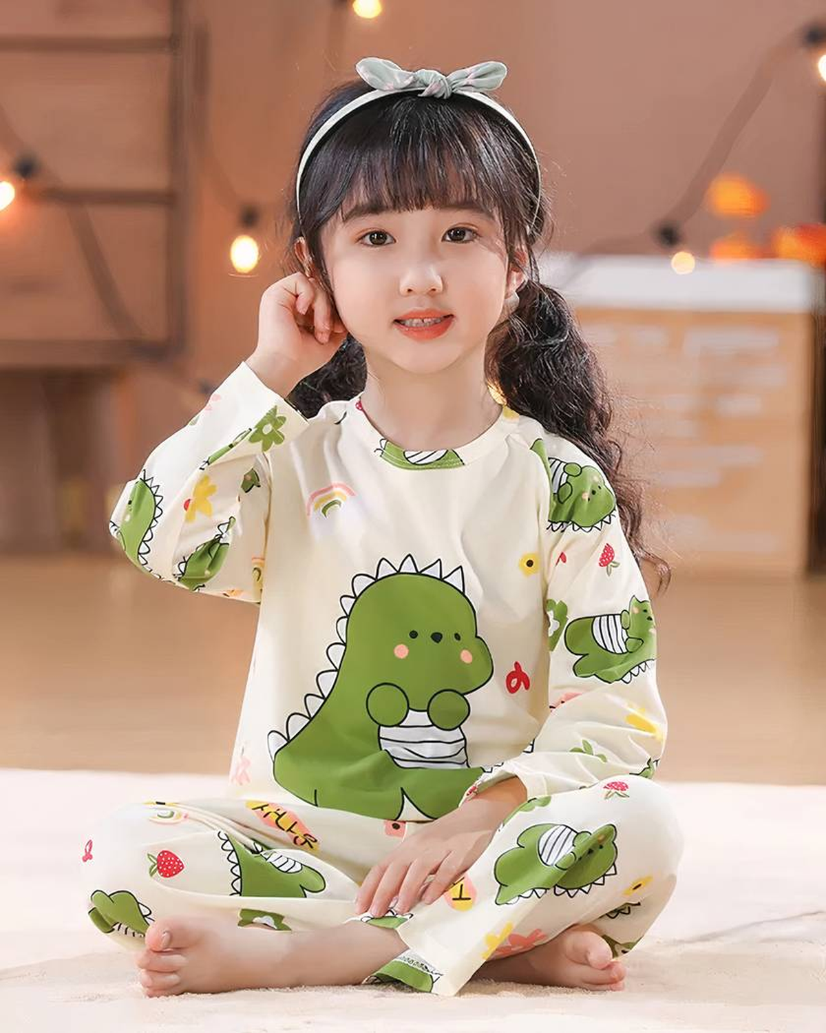 Fille souriante portant le pyjama dinosaure vert de mi-saison