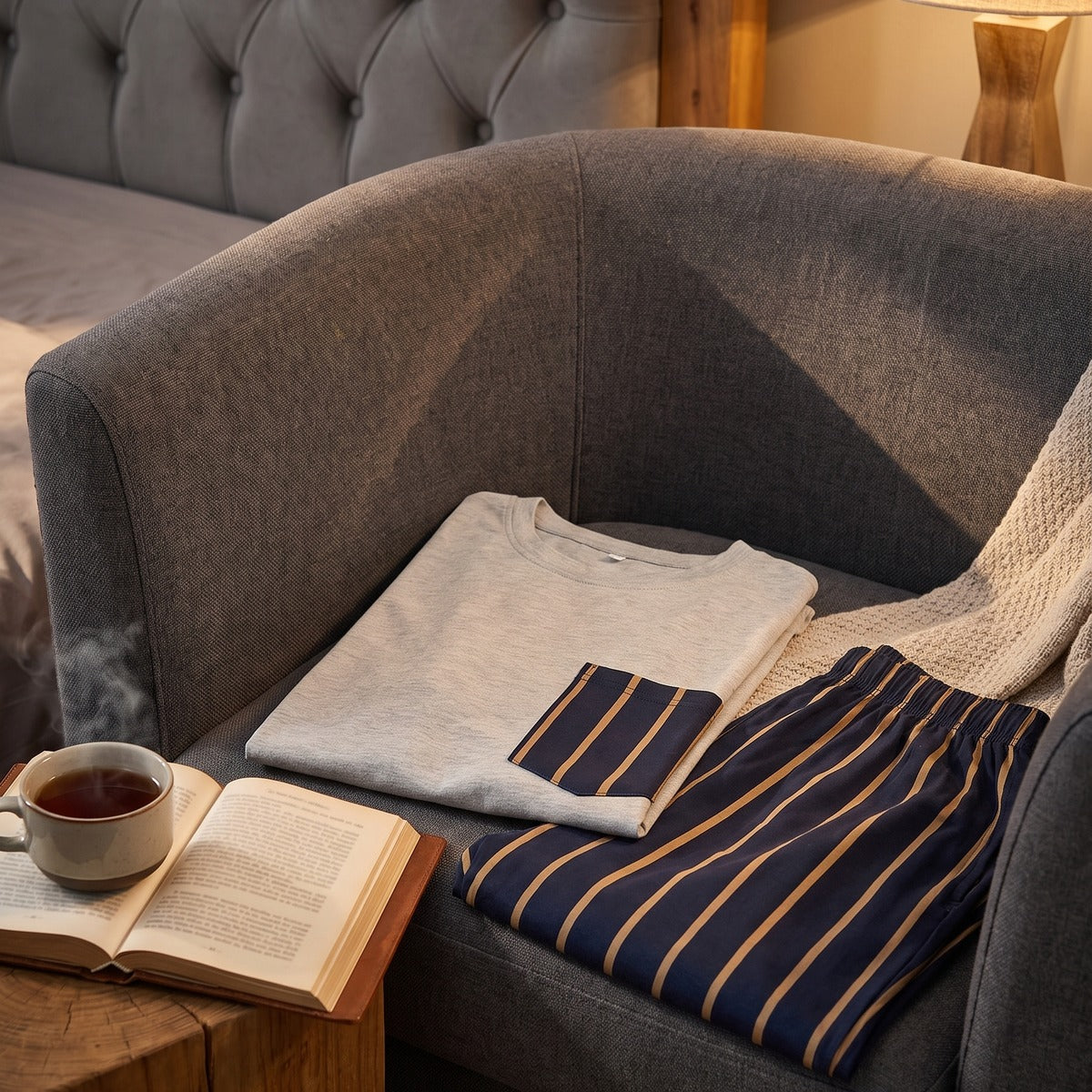 Ambiance boudoir tamisé, pyjama plié sur fauteuil, livre et tasse de thé Image