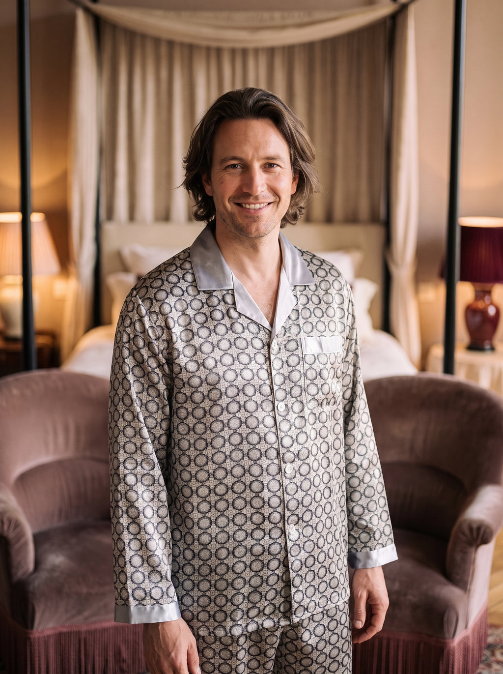 Homme souriant portant le pyjama deux pièces gris à motifs noirs dans une chambre boudoir