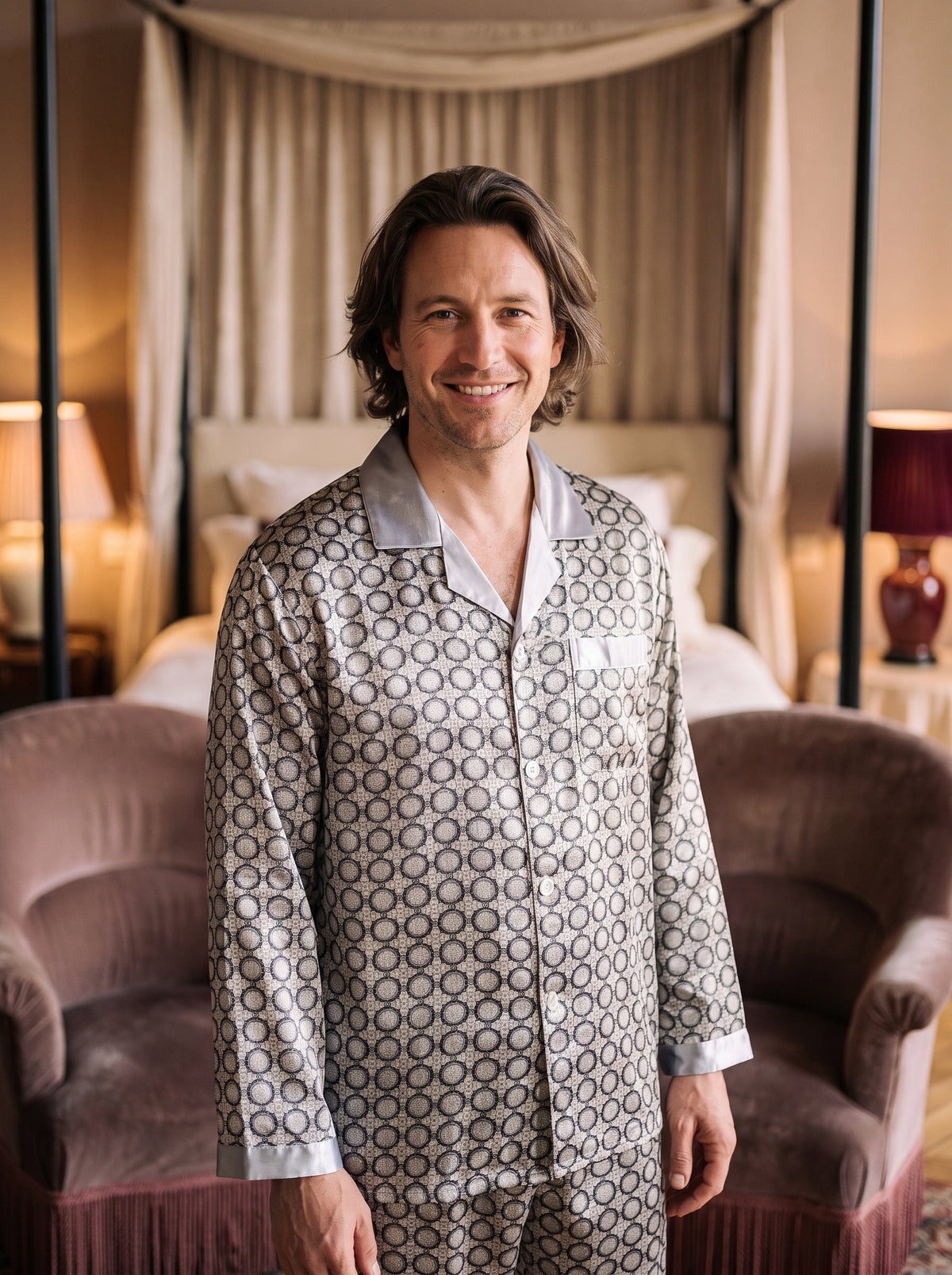 Homme souriant portant le pyjama deux pièces gris à motifs noirs dans une chambre boudoir