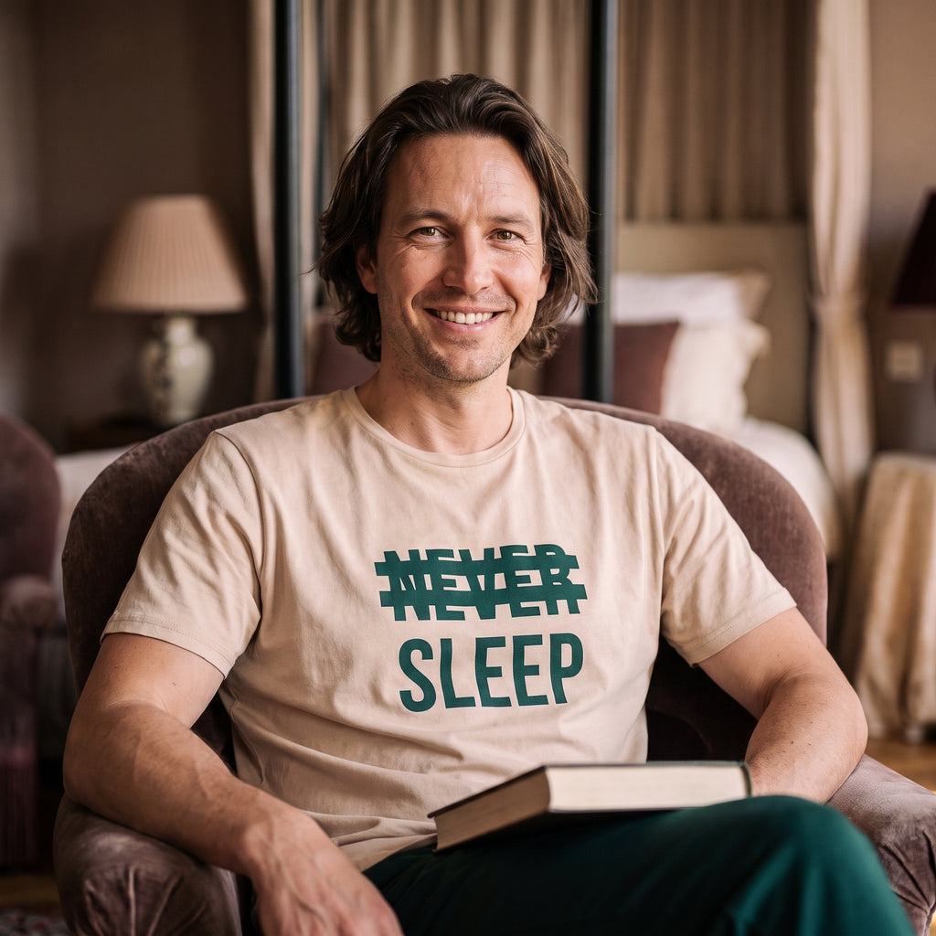 Homme souriant en pyjama Never Sleep installé dans un fauteuil avec un livre