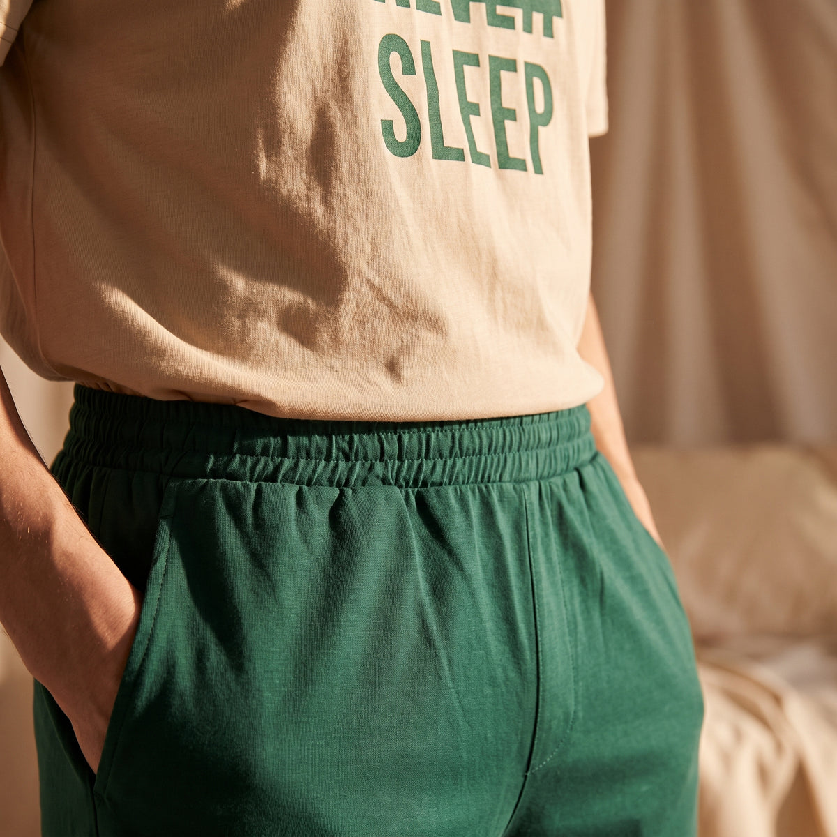 Gros plan sur la taille élastiquée du short vert et le t-shirt beige Never Sleep