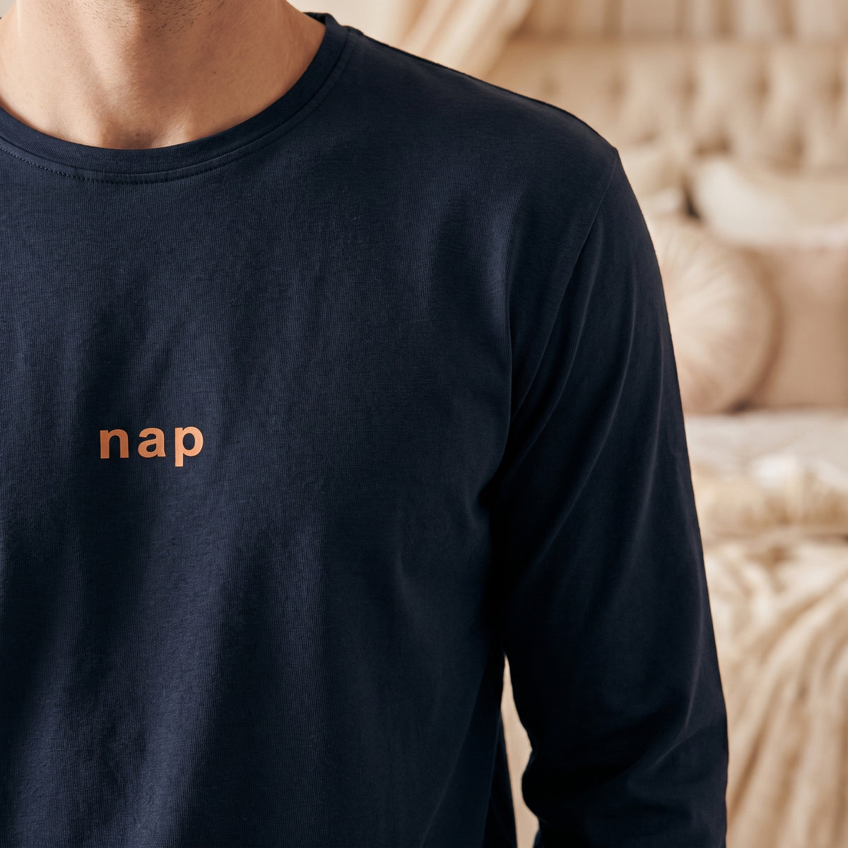 Gros plan du mot nap imprimé en orange sur la poitrine du pyjama bleu marine