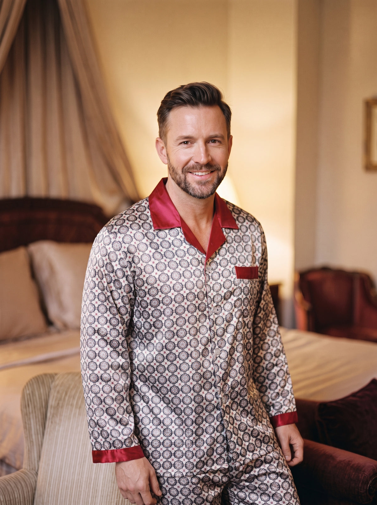 Homme souriant en pyjama à motif circulaire dans une chambre aux tons chaleureux