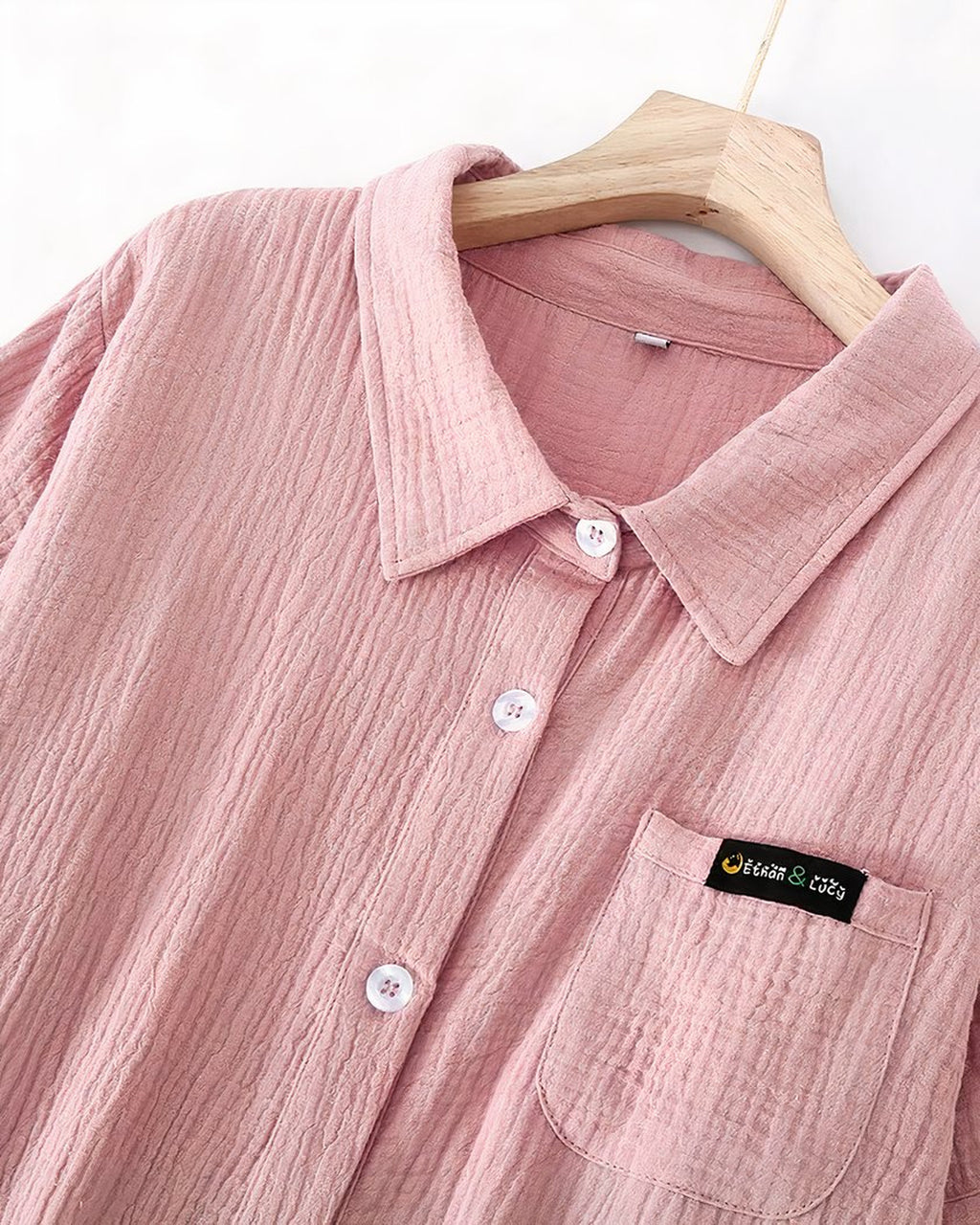 Haut d'une robe de chambre rose sur cintre : col à revers, boutonnage central et poche de poitrine