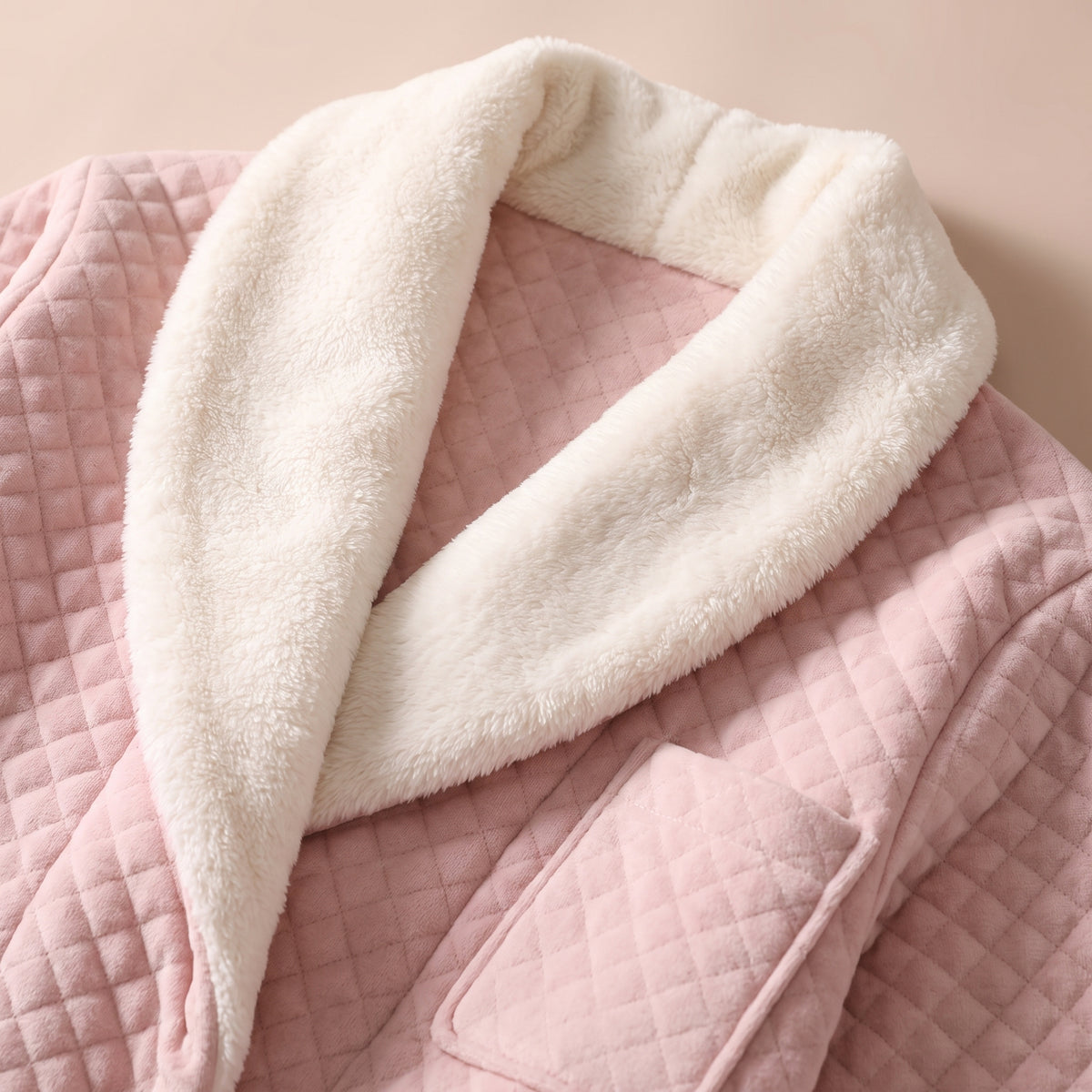 Gros plan carré sur le col châle en polaire crème de la robe de chambre matelassée rose