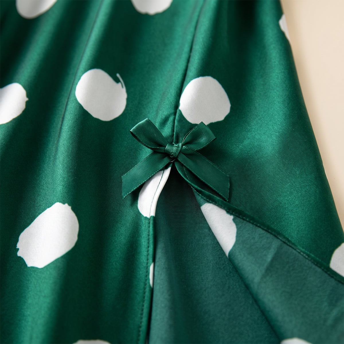 Gros plan sur le petit nœud et la fente latérale de la robe de nuit verte à pois