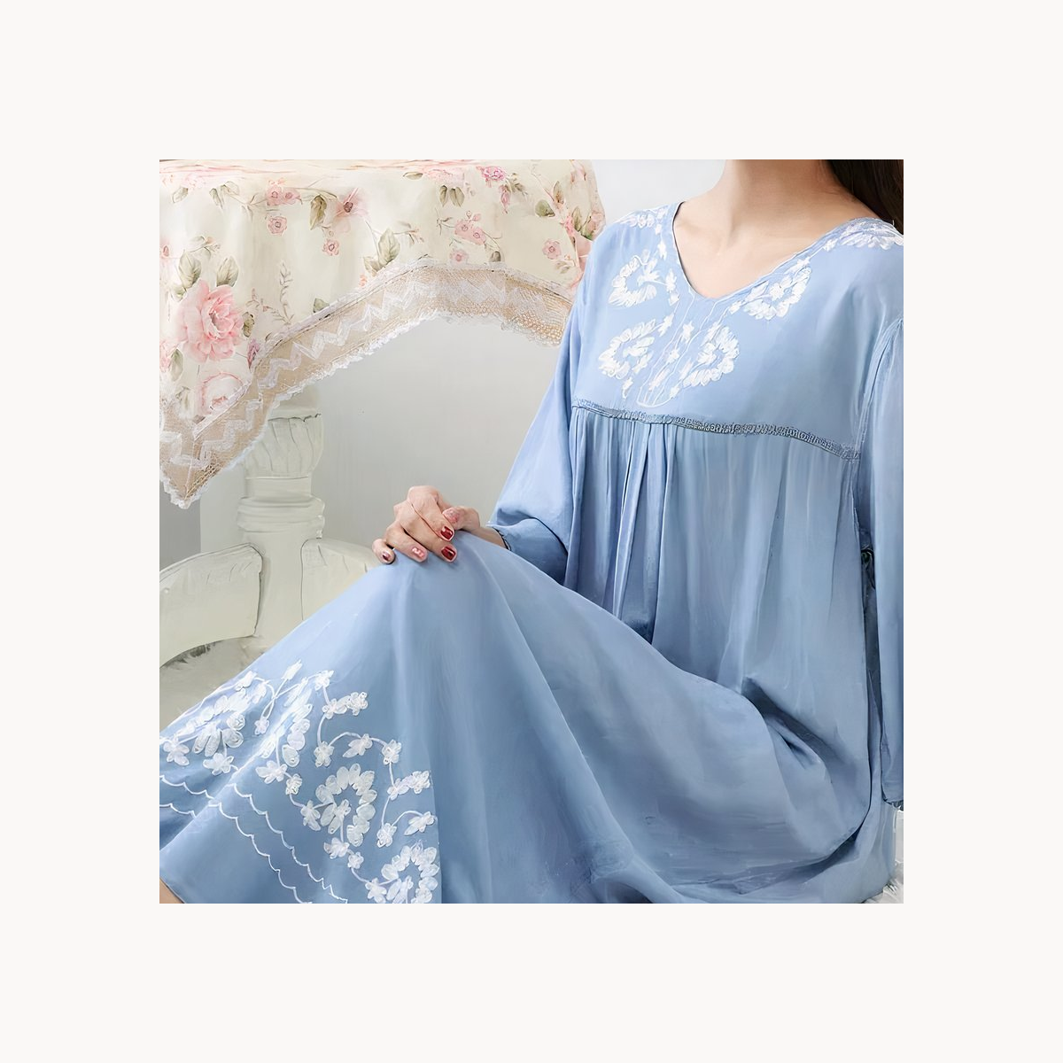 Détail des broderies blanches et des plis de la chemise de nuit bleue