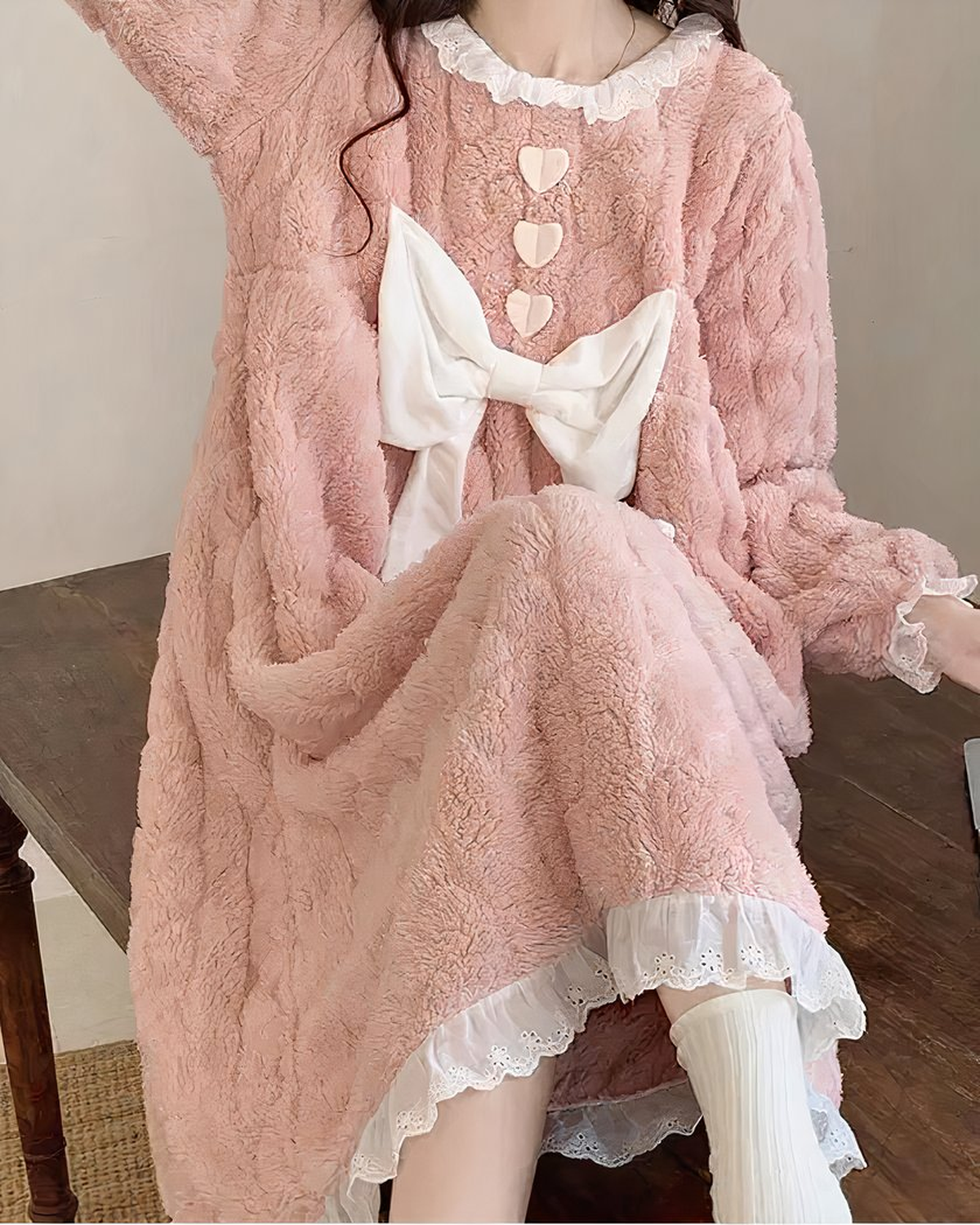 Chemise de nuit rose duveteuse portée assise, la jupe drapée sur les jambes et le volant de dentelle blanche qui dépasse sous l'ourlet
