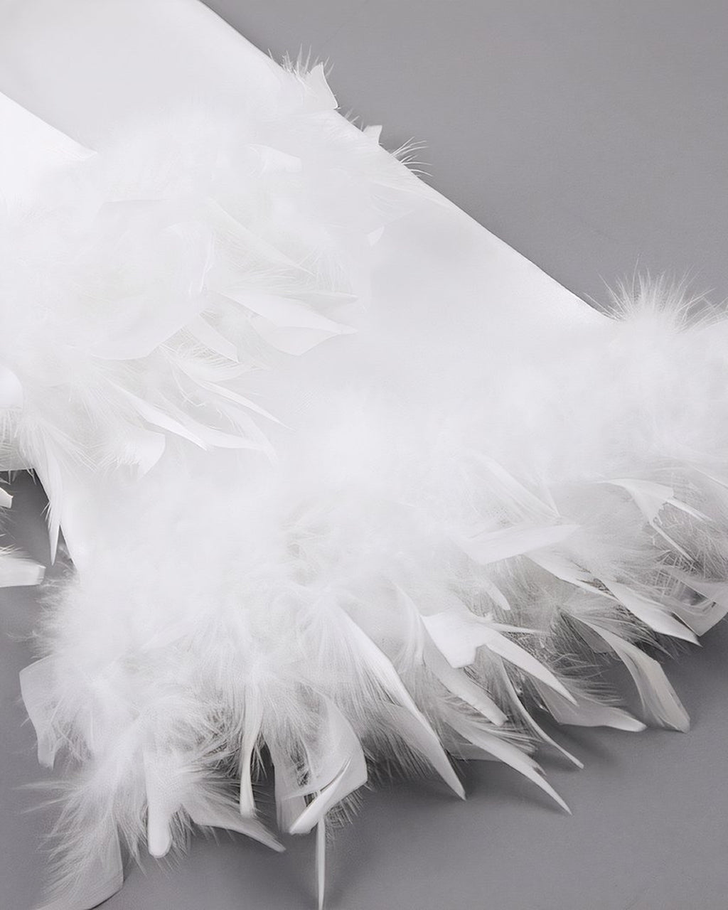 Détail de la bande de plumes cousue au bord du poignet du peignoir de satin