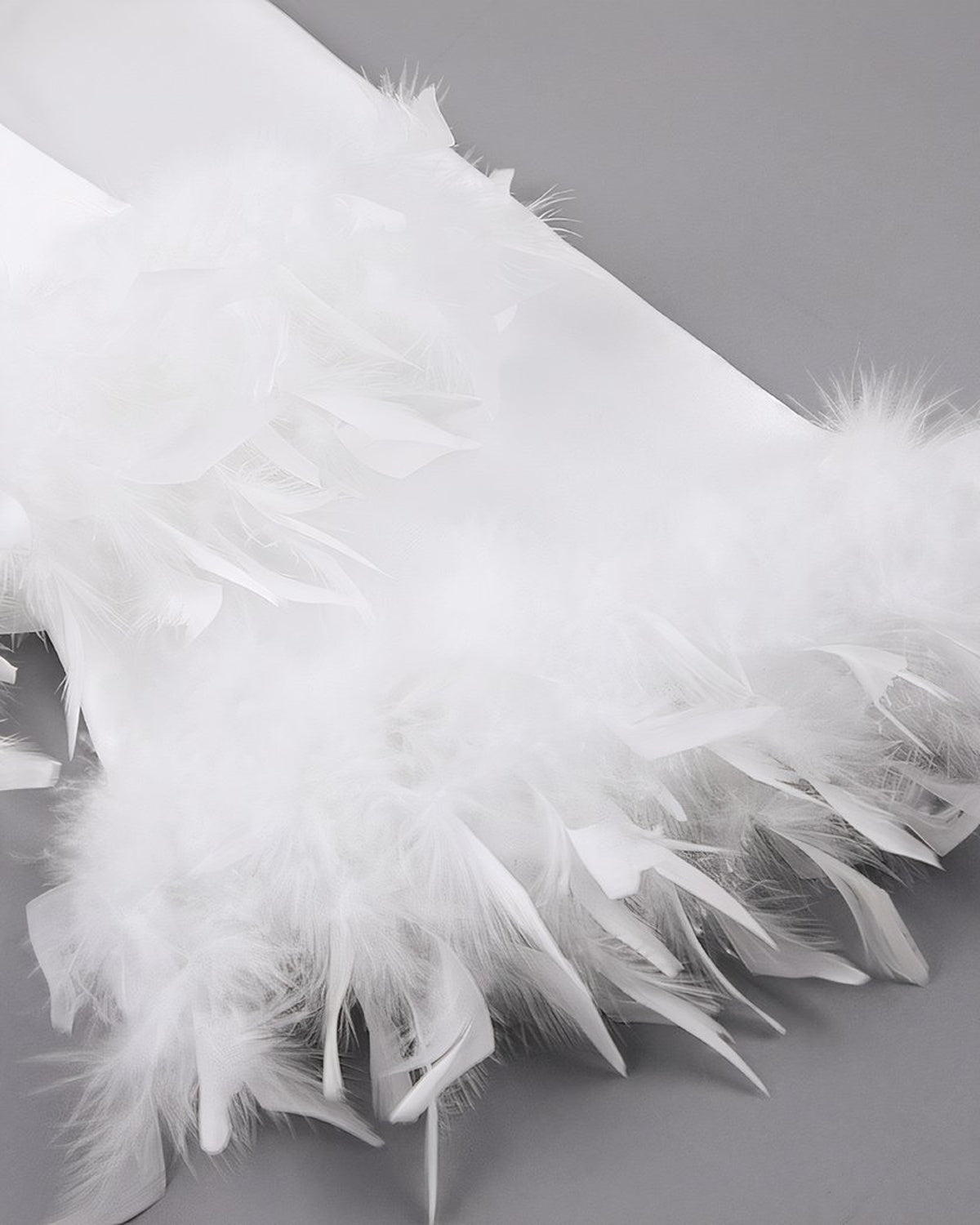 Détail de la bande de plumes cousue au bord du poignet du peignoir de satin