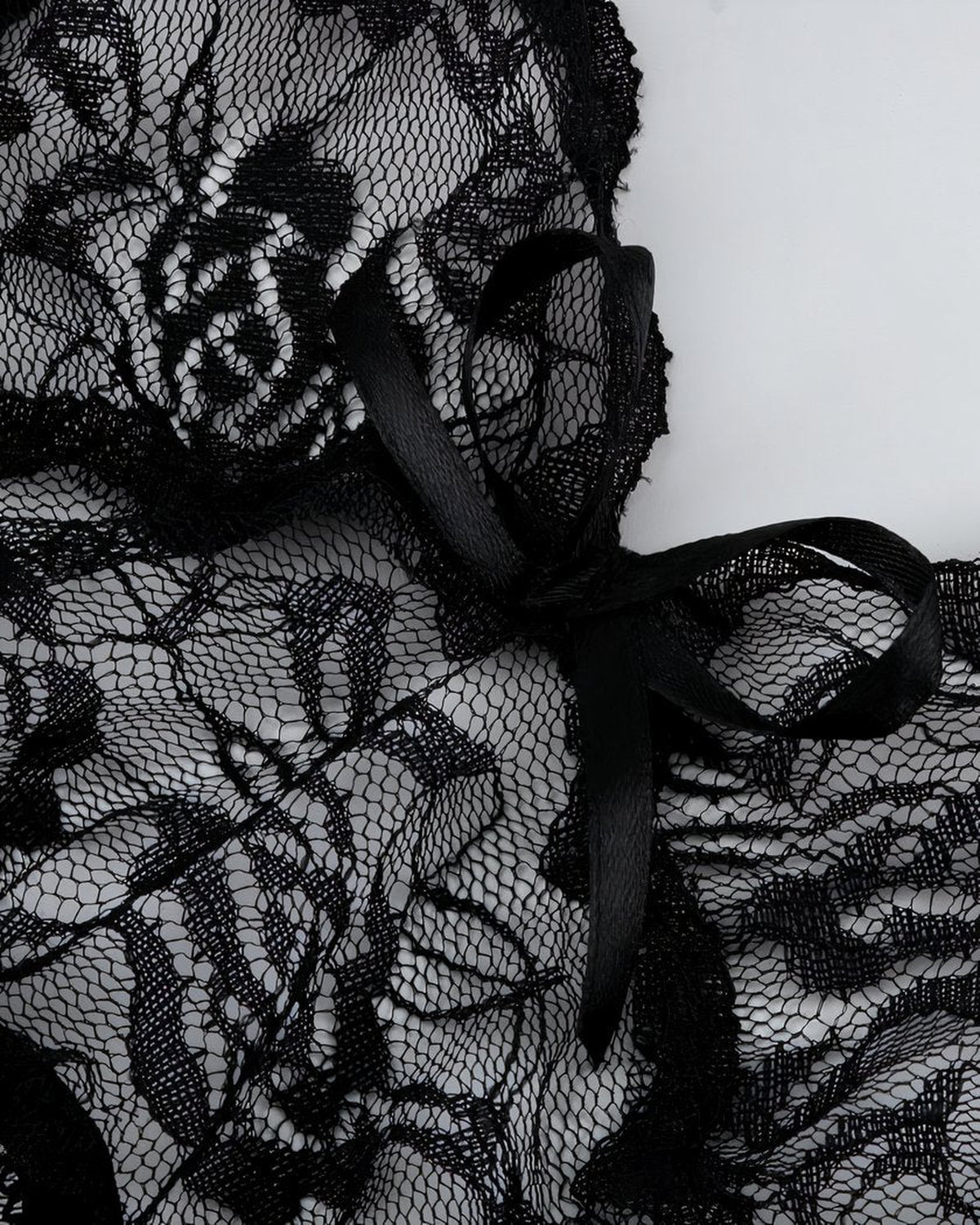 Gros plan sur la dentelle florale et le noeud satiné de la nuisette noire