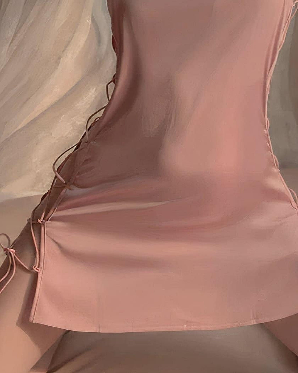 Gros plan sur le laçage latéral et le nœud papillon de la nuisette rose en satin