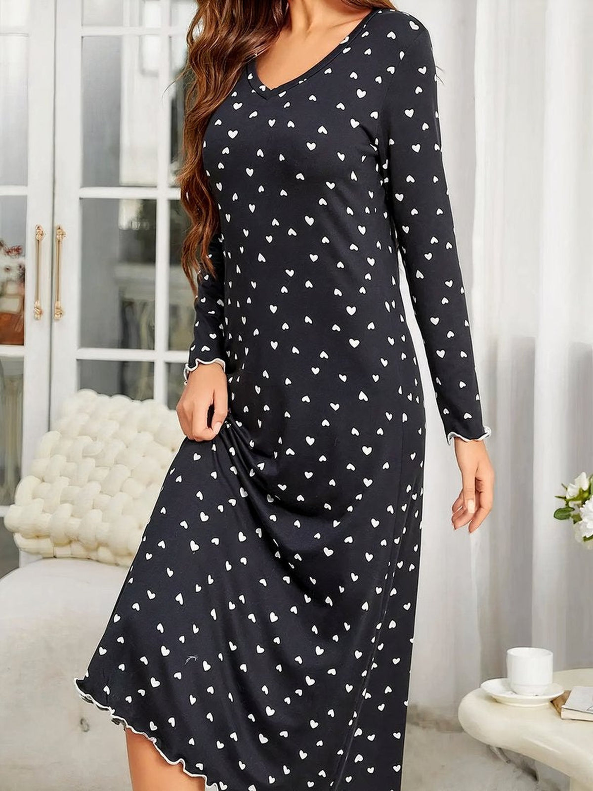 Chemise de nuit noire a coeurs blancs vue de trois quarts, bordure volantee a l'ourlet
