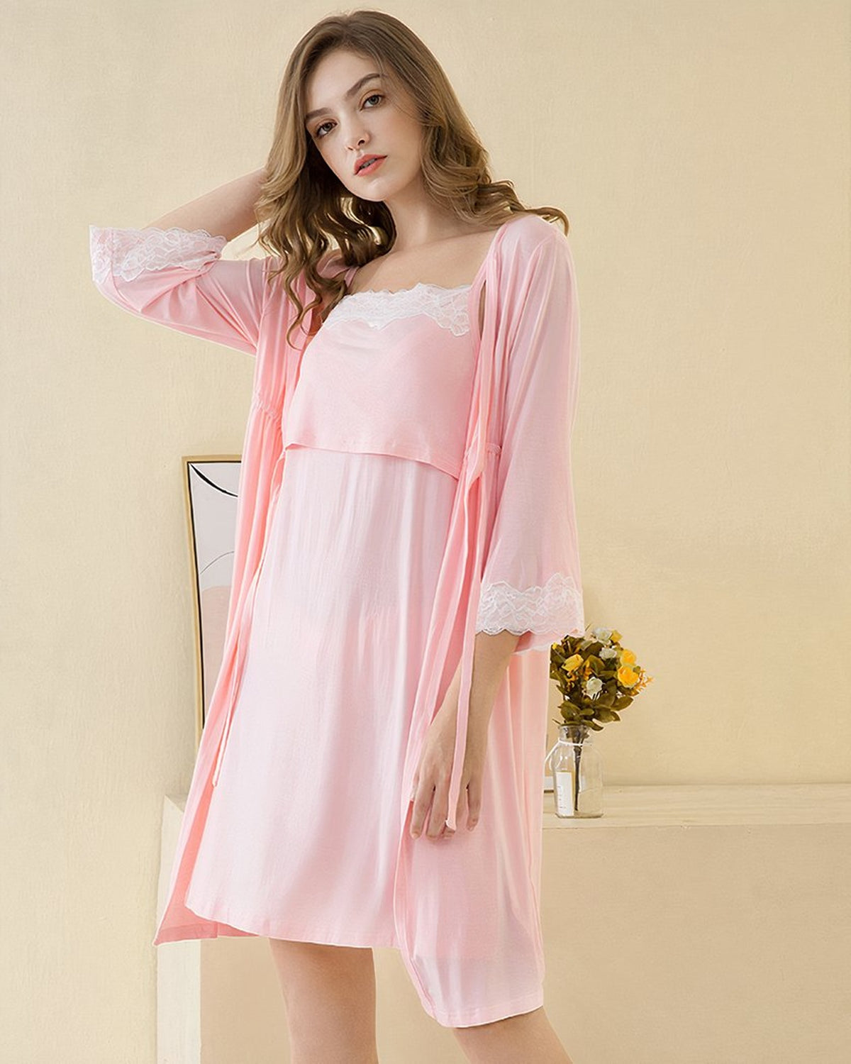 Femme enceinte portant l'ensemble nuisette et kimono rose, vue de face dans un interieur doux