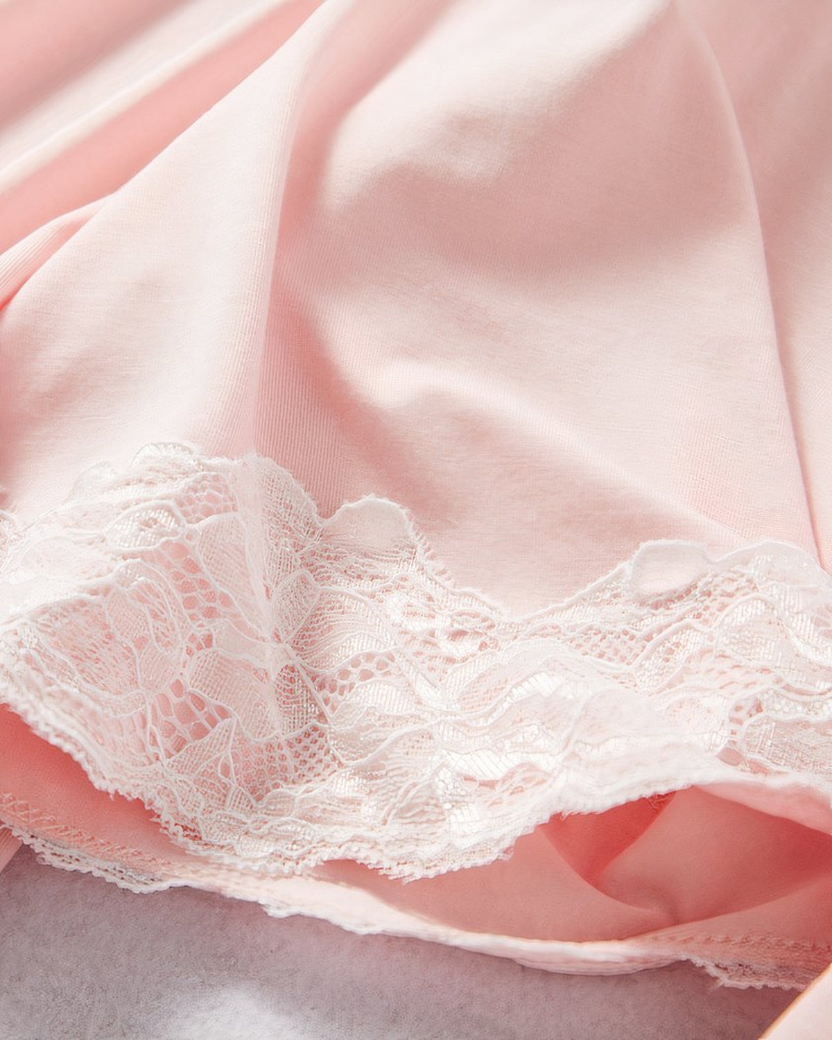 Detail de la dentelle blanche et du tissu rose poudre de la nuisette grossesse
