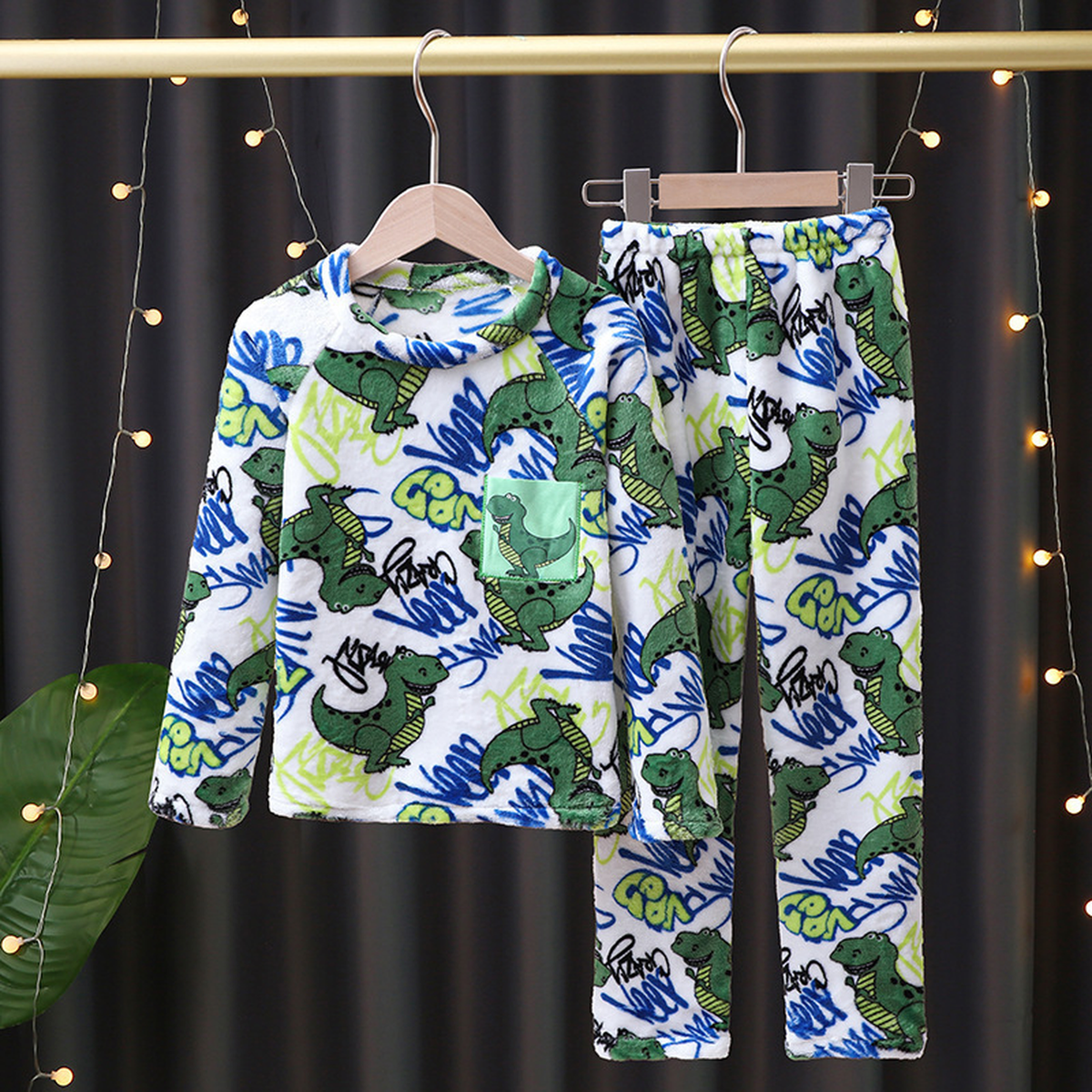 Pyjama blanc imprimé de dinosaures verts, bleus et anis, présenté sur cintre