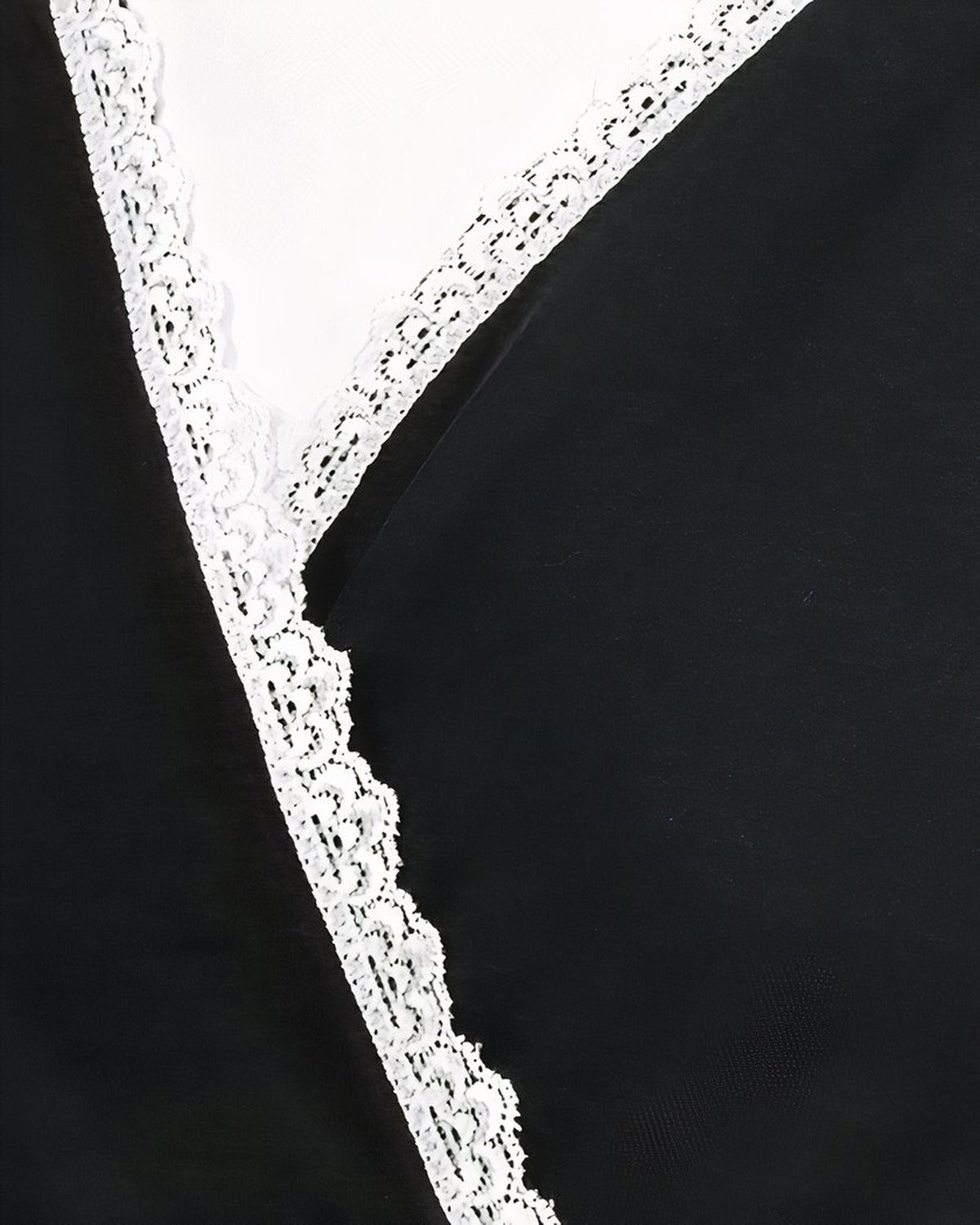 Détail de l'encolure croisée et de la dentelle blanche de la nuisette de maternité noire