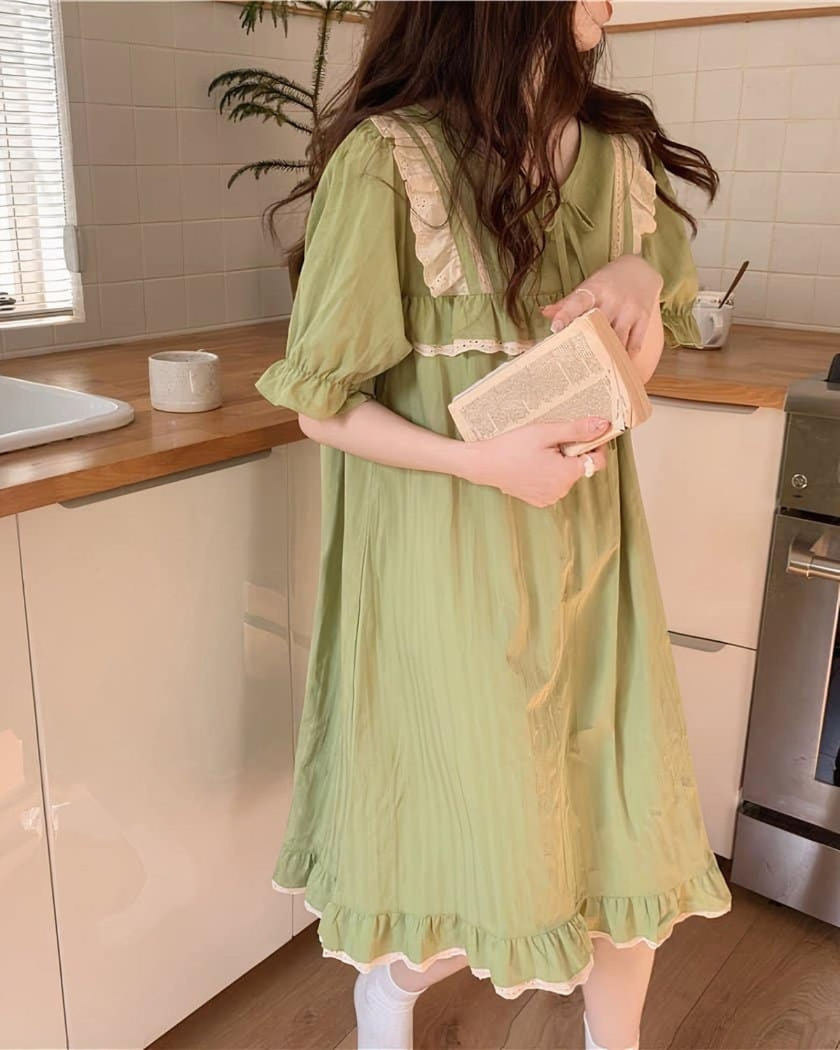 Coupe fluide de la nuisette verte en coton portee debout dans une cuisine lumineuse
