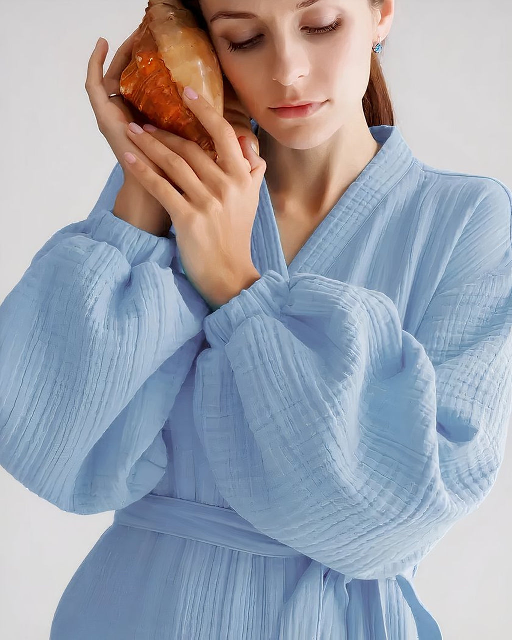 Peignoir spa en coton gaufré bleu ciel, modèle de près tenant un coquillage, photo d'origine